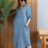 Turquoise linen summer dress with asymmetrical hem and long sleeves worn by a person standing, showcasing the dress's elegant design and vibrant azure color.