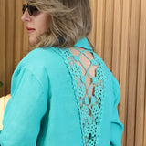A turquoise linen dress featuring an asymmetrical hem and long sleeves, styled for summer wear.