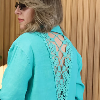A turquoise linen dress featuring an asymmetrical hem and long sleeves, styled for summer wear.