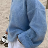 A person wearing a turquoise plush crewneck sweater with cozy soft-touch fabric, paired with jeans. The sweater features long sleeves and has a relaxed fit, perfect for winter. The individual is seen from the waist up.