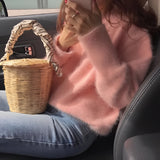 
Person wearing a pink, plush crewneck sweater with a soft-touch texture, ideal for cozy winter wear, against a light background. A hand is partially visible, suggesting the sweater's comfortable fit.