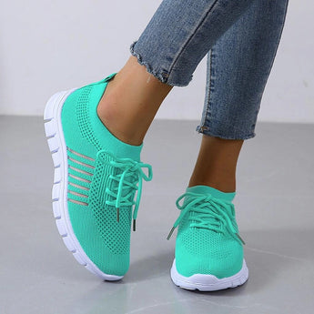 Turquoise women's breathable mesh sneakers, lightweight running shoes, shown on a person wearing them with white legs and denim pants.