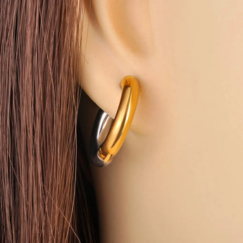 Two-tone gold and silver stainless steel hypoallergenic hoop earrings displayed on a wooden surface.
