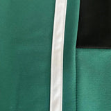 Unisex black turtleneck tracksuit set featuring green stripe joggers. The tracksuit includes long sleeves and a high collar, combining elements of sportswear with a fashionable design.