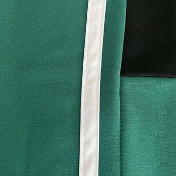 Unisex black turtleneck tracksuit set featuring green stripe joggers. The tracksuit includes long sleeves and a high collar, combining elements of sportswear with a fashionable design.