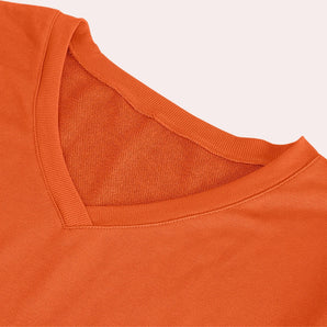 Unisex orange cotton blend crew neck sweater displayed on a wooden background, highlighting its lightweight and breathable fabric with long sleeves.