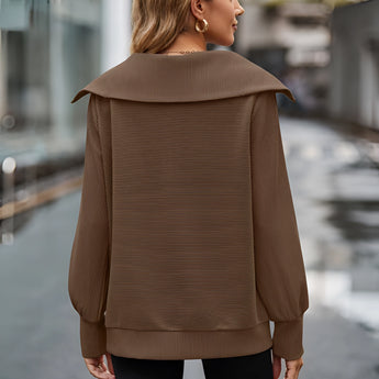 Urban Chic Brown Oversized Hooded Cape Sweater being worn by a person, showcasing its loose fit and long sleeves, with the hood draped over the shoulders, highlighting a fashionable and cozy outerwear style.