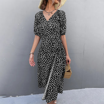A stylish black and white polka dot wrap midi dress with a V-neckline, featuring short sleeves and a fitted waist, perfect for summer fashion. The dress is modeled in an XL size, paired with a chic fedora hat for a complete look.