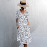 V-neck black and white polka dot wrap midi dress with short sleeves and fitted waist, styled for summer fashion.