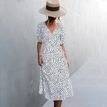 V-neck black and white polka dot wrap midi dress with short sleeves and fitted waist, styled for summer fashion.
