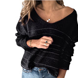 A woman wearing a black and white striped boho chic sweater with a v-neck, styled with jeans. The sweater features long sleeves and a relaxed fit, suitable for fall fashion.
