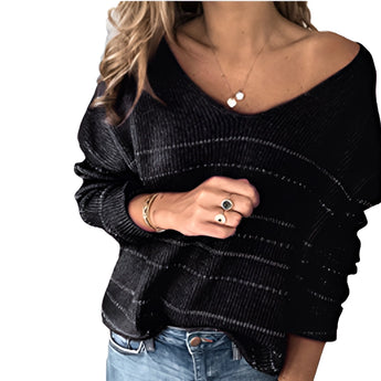 A woman wearing a black and white striped boho chic sweater with a v-neck, styled with jeans. The sweater features long sleeves and a relaxed fit, suitable for fall fashion.