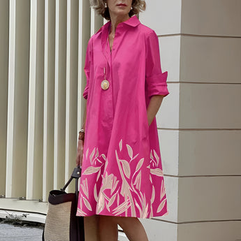 Vibrant asymmetric dress featuring a fuchsia and orange color block design, showcased in a 4XL size. The dress has a stylish shoulder cut, a round neck, and long sleeves, accentuating a cool, fashion-forward look. The predominant color is pink, enhanced with magenta tones.