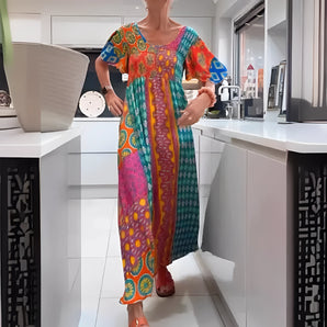 A woman is wearing a vibrant ethnic print kaftan dress with bohemian style, featuring an array of colors including orange, purple, and electric blue. The dress is designed as a loose-fitting one-piece garment, suitable as a beach cover-up. She stands in a fashionable pose, showcasing the flowy sleeves and the relaxed fit around the waist. The dress is in a 3XL size, perfect for formal or casual events.