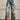 Woman wearing Vibrant Floral Print Bell-Bottom Jeans in Blue Forest color, high-waist, wide-leg denim with a boho style, size 5XL.