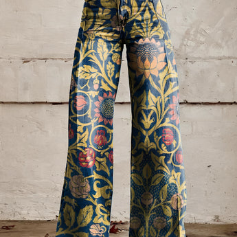 A pair of dark blue, high-waist bell-bottom jeans with a vibrant floral print, shown in size 5XL, worn by a person standing on a road surface.