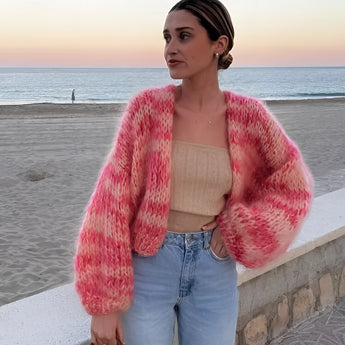 Handmade wool boho chic sweater in vibrant multicolor patchwork with a large size, featuring shades of pink and intricate designs, worn by a model with styled hair and accessorized outerwear.