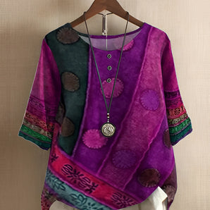 Vibrant patchwork boho blouse in purple with ethnic batwing sleeves and a round collar, featuring pink accents, displayed on a clothes hanger.