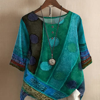 Vibrant patchwork boho blouse in green with purple ethnic patterns, featuring batwing sleeves and a relaxed fit, displayed on a clothes hanger.