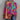 A vibrant pink-orange one-shoulder asymmetric summer blouse displayed against a neutral background, showcasing its unique design with a focus on the shoulder and sleeve area, emphasizing the bold color and stylish cut.