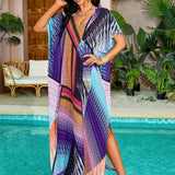 A woman wearing a vibrant print kaftan dress with tropical and luxurious resort styling, posing against a lush green background with houseplants and water elements.