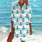 Woman wearing a vibrant tie-dye beach cover-up dress in mint green with anchor design, standing by the water.