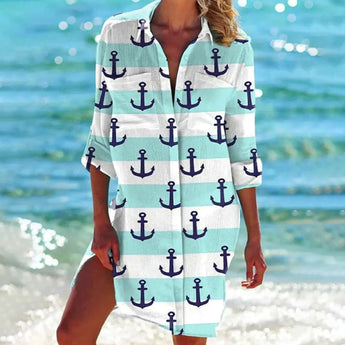 Woman wearing a vibrant tie-dye beach cover-up dress in mint green with anchor design, standing by the water.