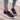 Black lightweight neon running shoes for women, featuring a breathable design with vibrant accents in purple and yellow, displayed on a light grey background.