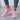 Women's lightweight running shoes in neon colors, primarily featuring rose and purple shades with black and white accents. The shoes are designed with breathable textile material and are shown on a standing leg, highlighting their fashionable appearance and fit.