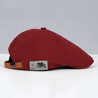 A red vintage-style newsboy cap made of cotton with an adjustable buckle strap, designed as a fashion accessory.