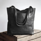 Vintage brown distressed leather tote bag with shoulder straps, handcrafted design, displayed with a luxurious and rustic appearance.