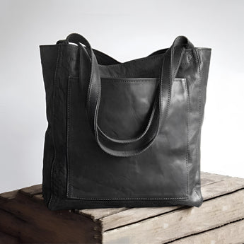 Vintage brown distressed leather tote bag with shoulder straps, handcrafted design, displayed with a luxurious and rustic appearance.