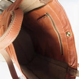 Vintage brown distressed leather tote bag, handcrafted luxury design, shown from the side with shoulder strap and detailed stitching.