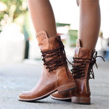 Vintage brown leather lace-up boots with a distressed style, featuring a convenient side zipper, displayed on a wooden surface.