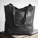 Vintage distressed leather tote in black, handmade rustic over-shoulder bag, with a rectangular shape, suitable as a fashion accessory or business bag.