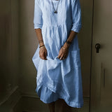 Vintage white linen dress in a bohemian loose fit, featuring lightweight fabric perfect for summer. The dress has a dress shirt style with sleeves, a collar, and a defined waist. The model is wearing sunglasses, showcasing the dress's elegant design and knee-length style, suitable for a relaxed fashion-forward look.