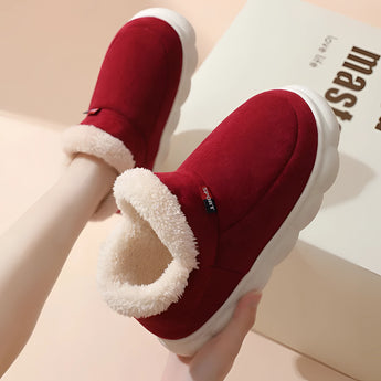 Warm fleece-lined winter slippers for women with a plush collar, being held by a hand showcasing their comfort and soft material.
