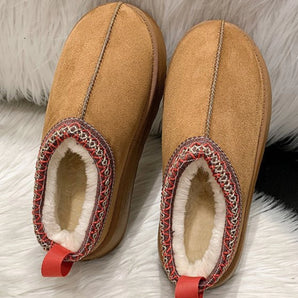 Warm sheepskin suede slippers with a non-slip sole in a close-up view, showcasing a magenta and carmine color palette with a textured pattern, featuring natural material and leather elements.