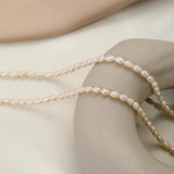 Waterproof hypoallergenic pearl choker necklace on a woman's neck, featuring elegant beach jewelry with a silver chain and metal beads.
