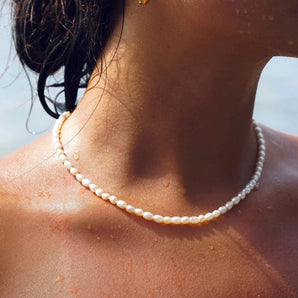 A close-up of a woman wearing a Waterproof Hypoallergenic Pearl Choker Necklace, showcasing the elegant beach jewelry around her neck.