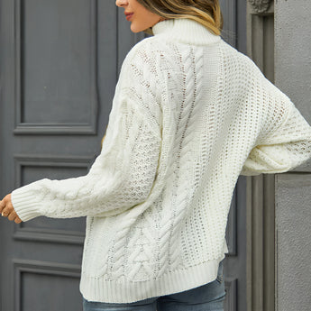 
A woman wearing a white cable knit turtleneck sweater paired with jeans, showcasing cozy winter fashion. The sweater features long sleeves and a high collar, emphasizing warmth and style.