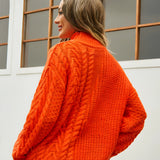 White cable knit turtleneck sweater for women showcasing cozy winter fashion, highlighting the intricate knit pattern and high collar, with visible sleeves and waist area.