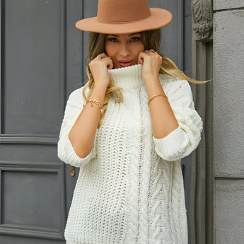 White cable knit turtleneck sweater worn by a woman, showcasing the cozy winter fashion style with visible details of the sweater's arm, shoulder, sleeve, and neck areas.