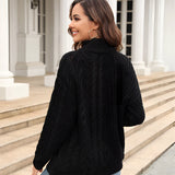 White cable knit turtleneck sweater worn by a woman standing and smiling, paired with jeans, showcasing cozy winter fashion.