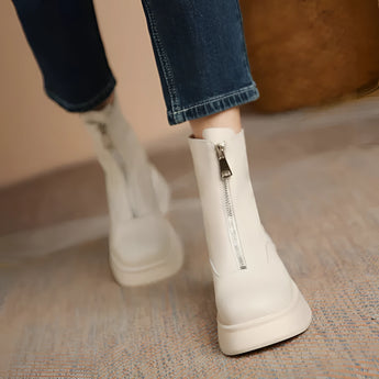 White chunky platform ankle boots for women with a zipper, styled with casual jeans and standing on a wooden floor.