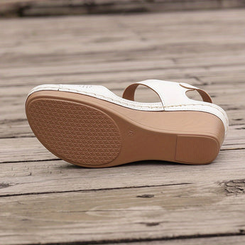 White floral wedge sandals with beaded strap and cutout design, featuring a brown wooden wedge heel and beige leather detailing.