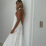 White halterneck tiered midi dress with an elegant design, suitable for summer resort wear or bridal parties, featuring a flattering waist and sleeveless style.