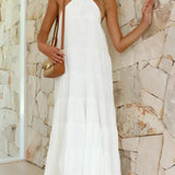 White halterneck tiered midi dress featuring an elegant design, suitable for summer resort wear, showcasing a sleeveless style with a fitted waist and flowing skirt.