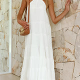 White halterneck tiered midi dress with sleeveless design, featuring a fitted waist and flowing skirt, ideal for elegant summer resort wear.