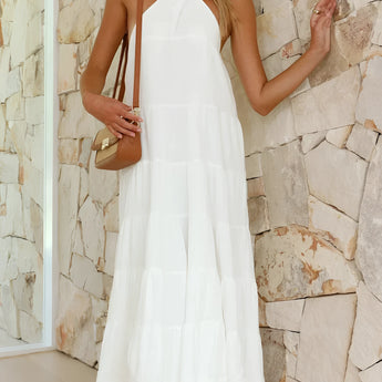 White halterneck tiered midi dress with sleeveless design, featuring a fitted waist and flowing skirt, ideal for elegant summer resort wear.